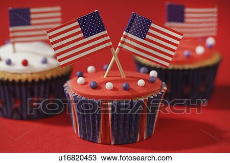 Stock Image - Three Iced Cupcakes Decorated With Small American Flags. Fotosearch