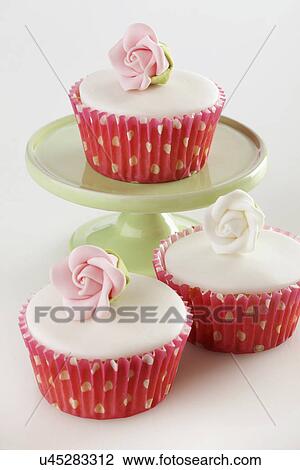 Three Perfect White Iced Cupcakes In Pink Polka Dot Cake Cases Decorated With Single Pink Sugar Craft Rose, One Cake On Green Cake Stand, Two On White Tabletop View Large Photo Image Stock Image - Three Perfect White Iced Cupcakes In Pink Polka Dot Cake Cases Decorated With Single Pink Sugar Craft Rose, One Cake On Green Cake Stand, Two On White Tabletop. Fotosearch