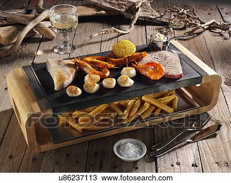 Tuna steaks king prawns and scallops on a hot lava stone with chips underneath View Large Photo Image Stock Image - Tuna steaks king prawns and scallops on a hot lava stone with chips underneath. Fotosearch