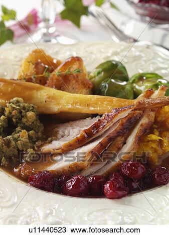 Stock Image - Turkey slices with roast potatoes parsnips herb stuffing Brussels Sprouts cranberries sweet potato mash gravy. Fotosearch