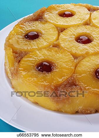 Stock Photography - Whole Pineapple Upside Down Cake With Cherry Garnish, On White Plate With Blue Tabletop. Fotosearch