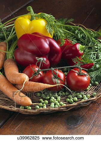 Stock Photography - Wicker basket raw vegetables tomatoes sweet red yellow peppers carrots peas. Fotosearch