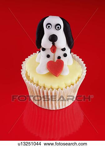 Yellow Iced Cupcake Decorated With Black And White Iced Dog Holding A Red Heart, On Red Background View Large Photo Image Picture - Yellow Iced Cupcake Decorated With Black And White Iced Dog Holding A Red Heart, On Red Background. Fotosearch