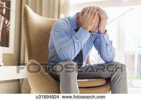Businessman with hands on head sitting on chair at home View Large Photo Image Picture - Businessman with hands on head sitting on chair at home. Fotosearch