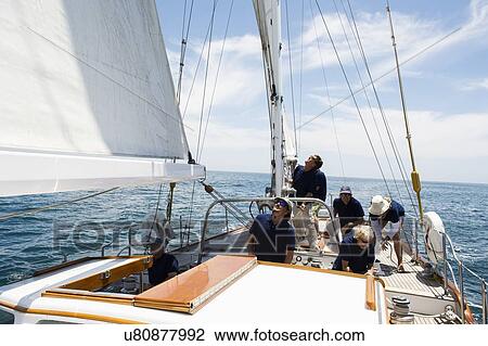 Stock Image - Crew working together on sailing yacht. Fotosearch