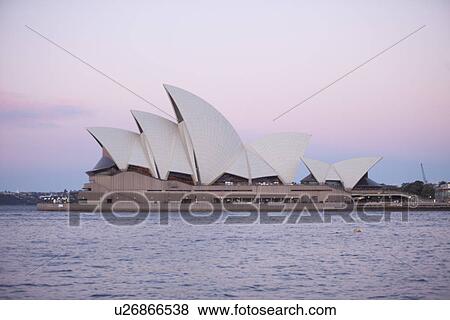 Stock Photo - Exterior of Opera house with sea in foreground at dusk, Sydney, Australia. Fotosearch