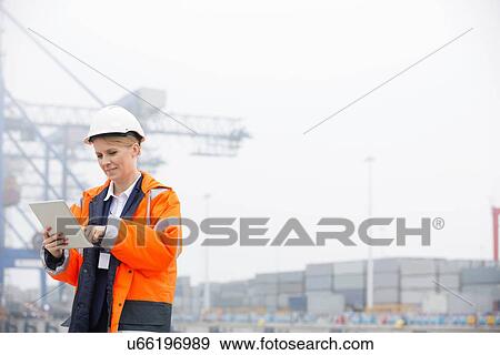 Female engineer using tablet computer in shipping yard View Large Photo Image Stock Photo - Female engineer using tablet computer in shipping yard. Fotosearch