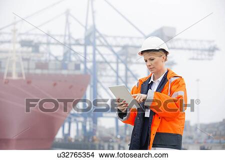 Female engineer using tablet PC in shipping yard View Large Photo Image Picture - Female engineer using tablet PC in shipping yard. Fotosearch