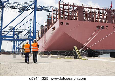 Full-length rear view of workers walking in shipping yard View Large Photo Image Stock Photography - Full-length rear view of workers walking in shipping yard. Fotosearch