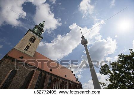 Stock Photography - Low angle view of St. Mary's Church and TV Tower in Berlin against cloudy sky, Germany, Europe. Fotosearch