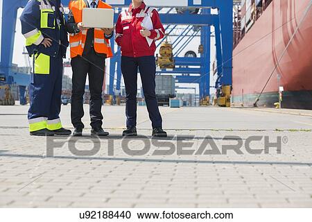 Low section of workers discussing in shipping yard View Large Photo Image Stock Image - Low section of workers discussing in shipping yard. Fotosearch