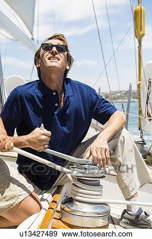Stock Photo - Men turning crank handle on yacht. Fotosearch