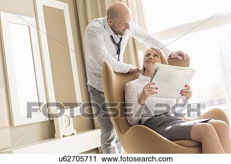 Mid adult business couple reading newspaper at home View Large Photo Image Stock Image - Mid adult business couple reading newspaper at home. Fotosearch