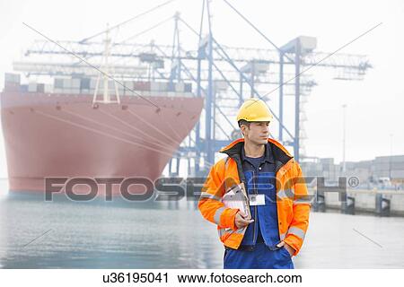 Mid adult man with clipboard in shipping yard View Large Photo Image Stock Image - Mid adult man with clipboard in shipping yard. Fotosearch