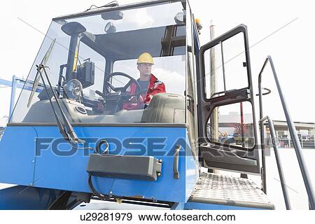 Mid adult worker operating forklift truck in shipping yard View Large Photo Image Stock Photo - Mid adult worker operating forklift truck in shipping yard. Fotosearch
