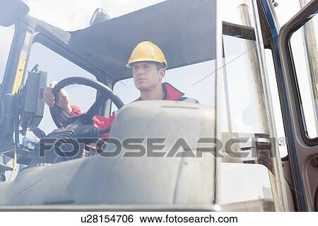 Mid adult worker operating forklift truck in shipping yard View Large Photo Image Stock Photograph - Mid adult worker operating forklift truck in shipping yard. Fotosearch