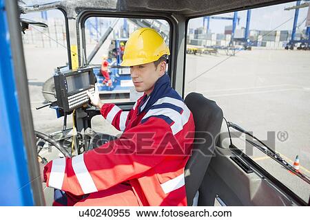 Stock Photography - Mid adult worker operating forklift truck in shipping yard. Fotosearch