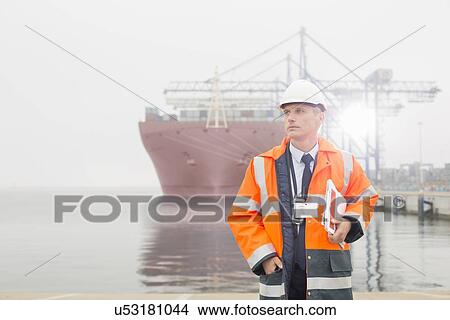 Picture - Portrait of middle-aged man holding walkie-talkie in shipping yard. Fotosearch