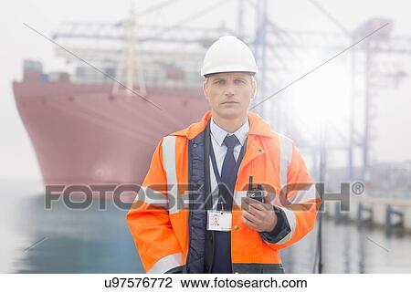 Portrait of middle-aged man holding walkie-talkie in shipping yard View Large Photo Image Stock Image - Portrait of middle-aged man holding walkie-talkie in shipping yard. Fotosearch