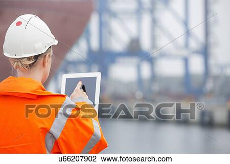 Rear view of female engineer using tablet PC in shipping yard View Large Photo Image Stock Image - Rear view of female engineer using tablet PC in shipping yard. Fotosearch