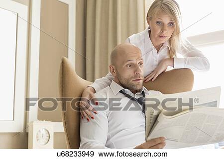 Shocked business couple reading newspaper at home View Large Photo Image Stock Photo - Shocked business couple reading newspaper at home. Fotosearch