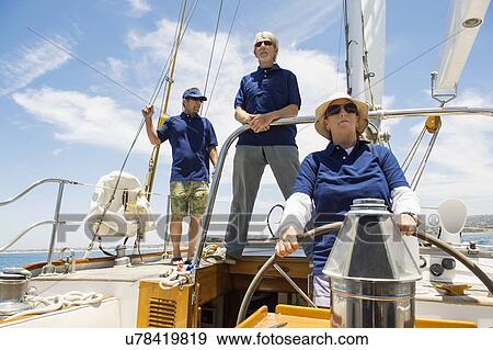 Woman steering yacht with friends in background View Large Photo Image Stock Photo - Woman steering yacht with friends in background. Fotosearch
