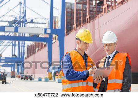 Worker taking sign of supervisor on clipboard in shipping yard View Large Photo Image Stock Image - Worker taking sign of supervisor on clipboard in shipping yard. Fotosearch