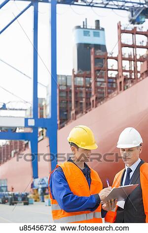 Worker taking sign of supervisor on clipboard in shipping yard View Large Photo Image Stock Image - Worker taking sign of supervisor on clipboard in shipping yard. Fotosearch