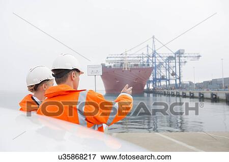 Stock Photo - Workers discussing in shipping yard. Fotosearch