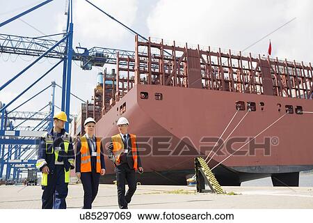 Stock Photo - Workers discussing in shipping yard. Fotosearch