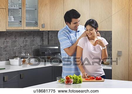 Affectionate man putting necklace on woman in kitchen View Large Photo Image Stock Photography - Affectionate man putting necklace on woman in kitchen. Fotosearch