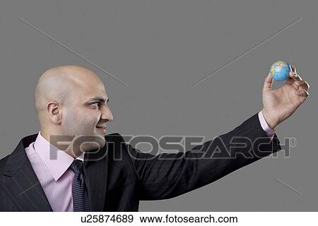 Bald businessman holding a tiny globe View Large Photo Image Stock Photo - Bald businessman holding a tiny globe . Fotosearch