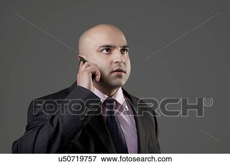 Stock Photo - Bald businessman talking on the mobile phone . Fotosearch