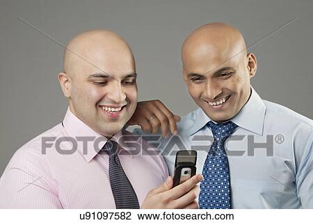 Bald executives looking at a mobile phone View Large Photo Image Stock Image - Bald executives looking at a mobile phone . Fotosearch