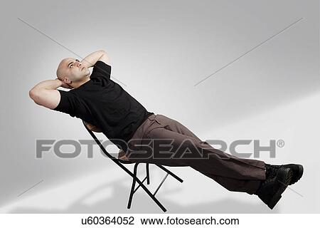 Bald man relaxing on a chair View Large Photo Image Stock Image - Bald man relaxing on a chair . Fotosearch