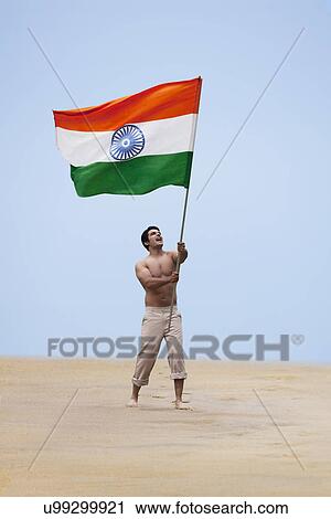 Stock Image - Bare chested man holding the Indian flag . Fotosearch
