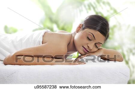Stock Photo - Beautiful young woman lying on massage table . Fotosearch