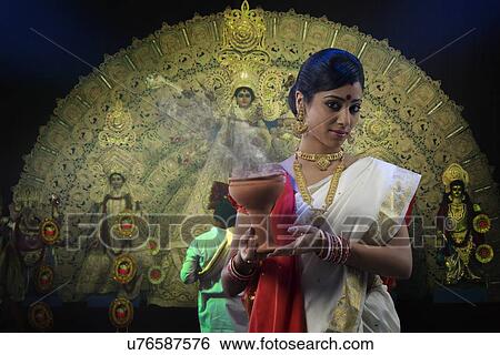 Stock Photograph - Bengali woman holding a dhunuchi . Fotosearch