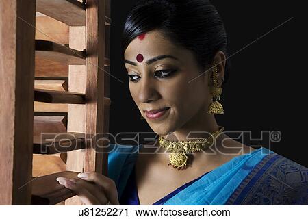 Stock Image - Bengali woman peeking out of a window . Fotosearch