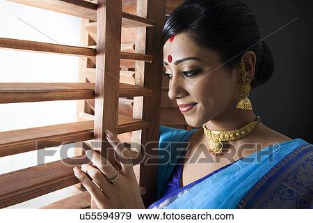Stock Photo - Bengali woman peeking out of a window . Fotosearch
