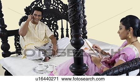 Bengali woman stitching while husband talks on a mobile phone View Large Photo Image Stock Image - Bengali woman stitching while husband talks on a mobile phone . Fotosearch