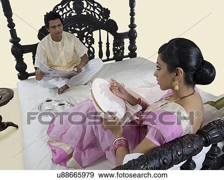 Bengali woman stitching while husband reads the newspaper View Large Photo Image Stock Photo - Bengali woman stitching while husband reads the newspaper . Fotosearch