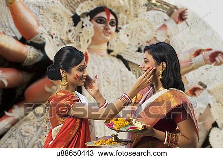 Stock Image - Bengali women putting colour on each others faces . Fotosearch