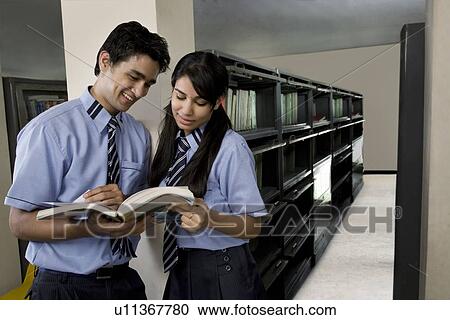 Boy and girl reading a book in a library View Large Photo Image Stock Image - Boy and girl reading a book in a library . Fotosearch