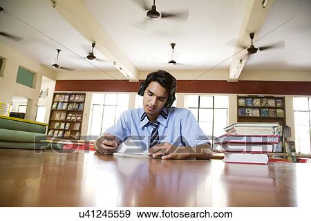 Stock Photo - Boy listening to music in a library . Fotosearch