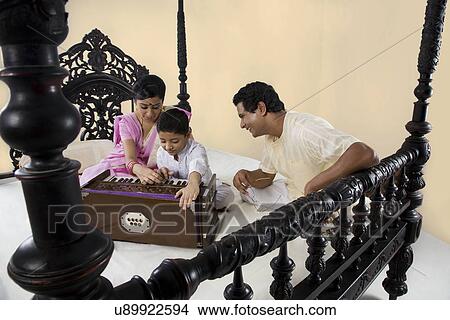 Picture - Boy playing on a harmonium . Fotosearch
