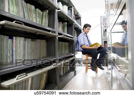 Boy reading a book in a school library View Large Photo Image Stock Image - Boy reading a book in a school library . Fotosearch