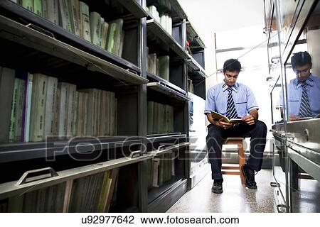 Boy reading a book in a school library View Large Photo Image Stock Image - Boy reading a book in a school library . Fotosearch
