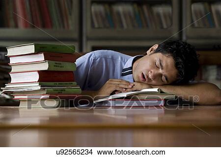 Boy sleeping on books in a school library View Large Photo Image Picture - Boy sleeping on books in a school library . Fotosearch