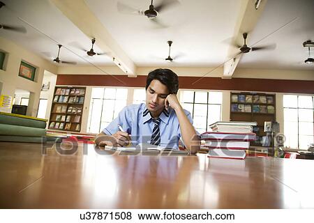 Boy studying in a school library View Large Photo Image Stock Photo - Boy studying in a school library . Fotosearch